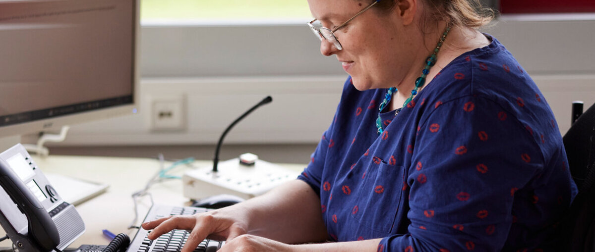 Eine junge Frau mit Beeinträchtigung an ihrem inklusiven Arbeitsplatz.