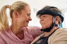 Auf dem Foto sind zwei Frauen, die sich vertrauensvoll anschauen. Eine Frau trägt einen Schutzhelm aus Leder.