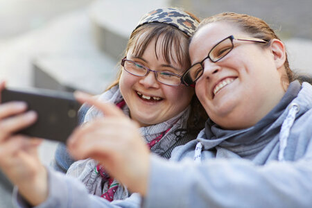 Zwei junge Frauen machen ein Selfie. Sie freuen sich.